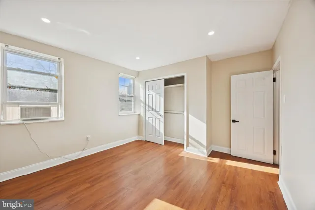 a view of an empty room with wooden floor and window