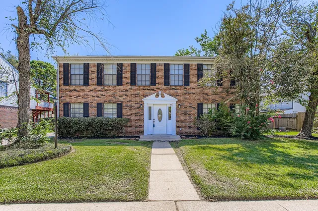 a front view of a house with a yard and trees