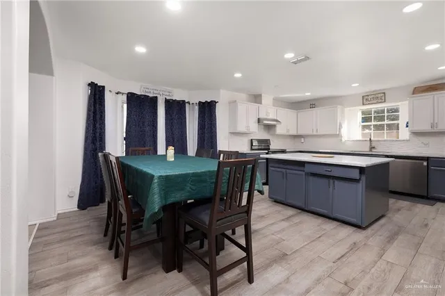 a kitchen with a dining table chairs and wooden floor