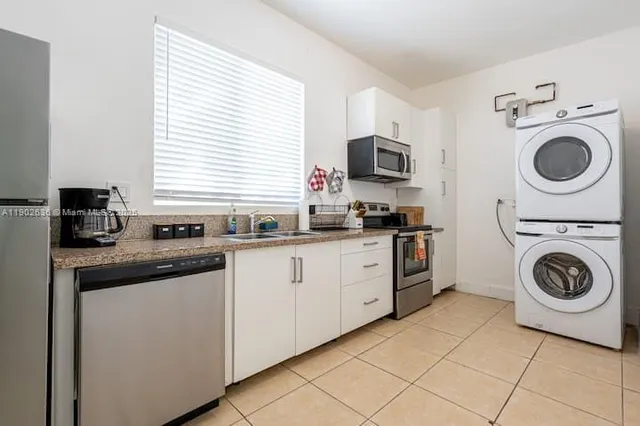 a kitchen with a sink and a stove top oven with white cabinets