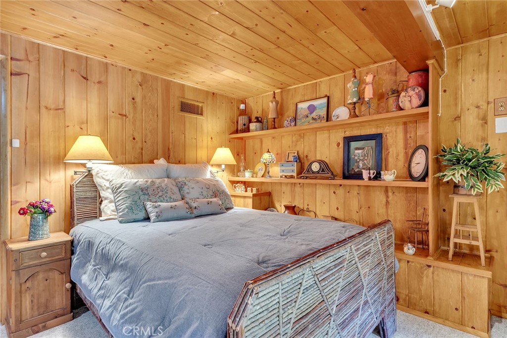 25300 Pine Crest Avenue Idyllwild, CA 92549 - Photo 51 of 75 Lower level primary bedroom with shelf displays containing Dolly's trinkets.