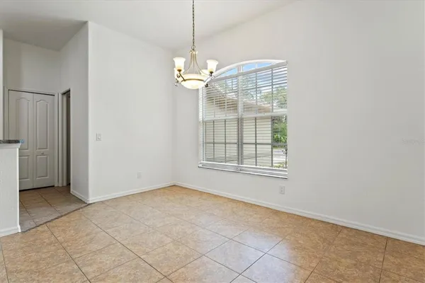 an empty room with chandelier fan and windows