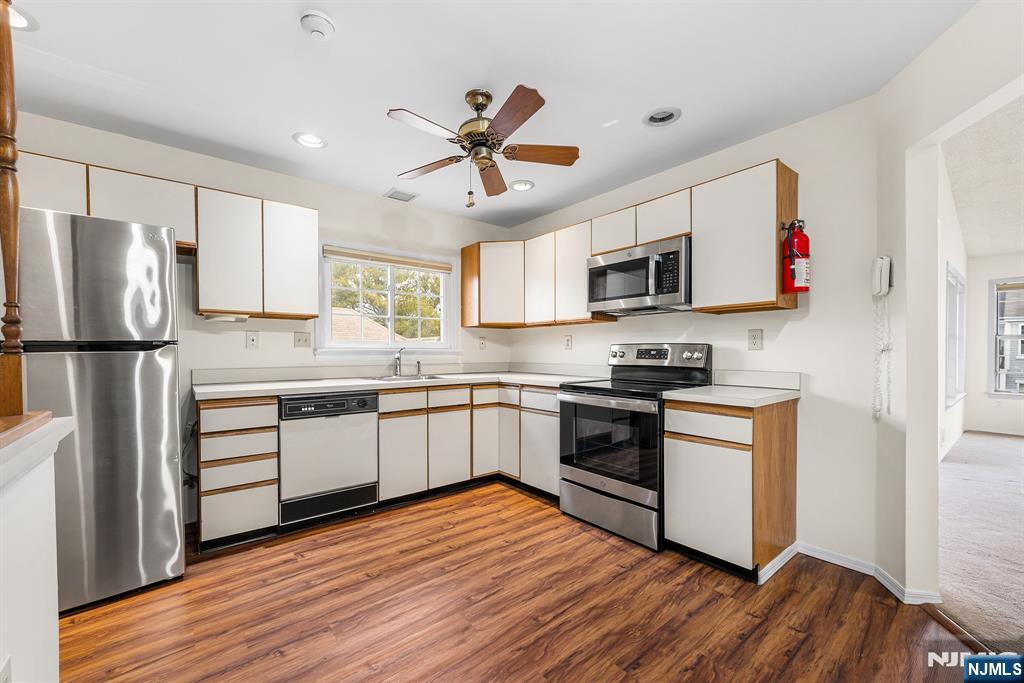 11A Rothwell Drive, Unit 11D Monroe Township, NJ 08831 - Photo 18 of 47 a kitchen with stainless steel appliances granite countertop a refrigerator a stove top oven a sink and dishwasher with wooden floor