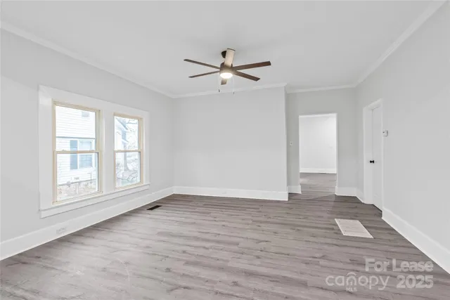 an empty room with wooden floor ceiling fan and windows