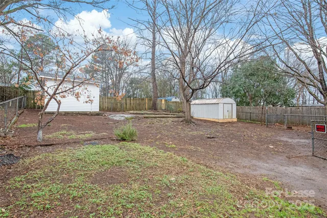 a backyard of a house with large trees and fence