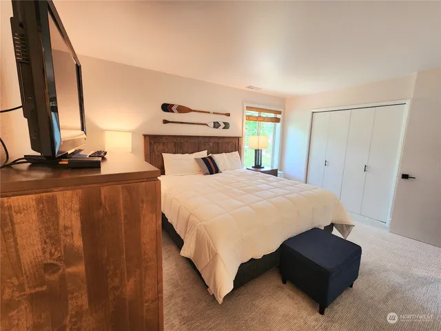 a bed sitting in a bedroom next to a window with pc on the table