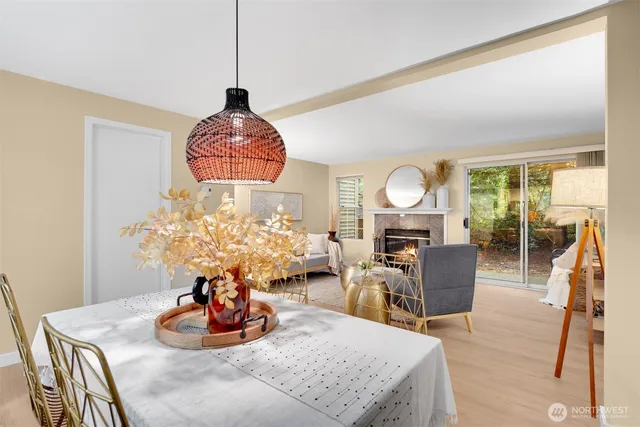 a dining room with wooden floor a chandelier a glass table and chairs