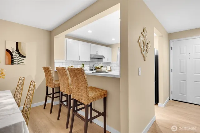 a kitchen with stainless steel appliances granite countertop a dining table chairs and a refrigerator