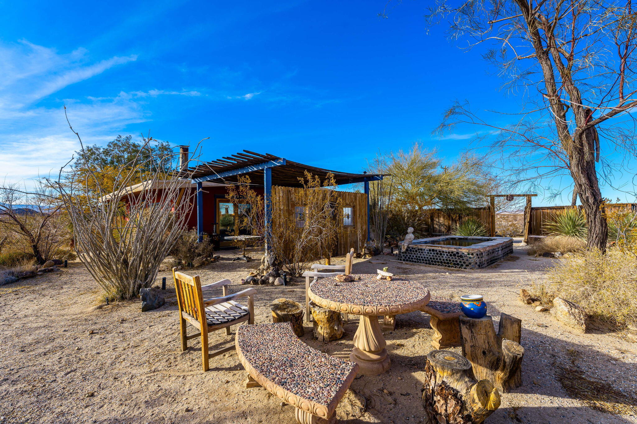 1776 Sunview Avenue Joshua Tree, CA 92252 - Photo 38 of 55 a view of a patio with table and chairs under an umbrella with wooden fence