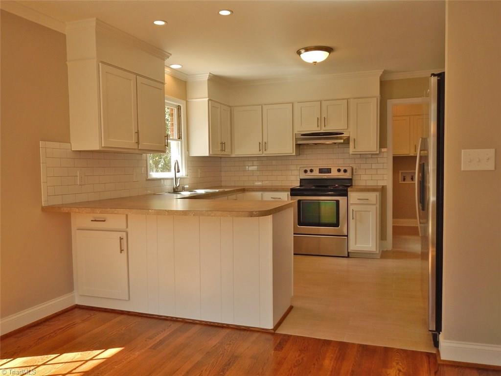 8007 Eastridge Road Oak Ridge, NC 27310 - Photo 8 of 29 The Kitchen is bright & white with stainless appliances , a beautiful tile floor & subway tile backsplash.