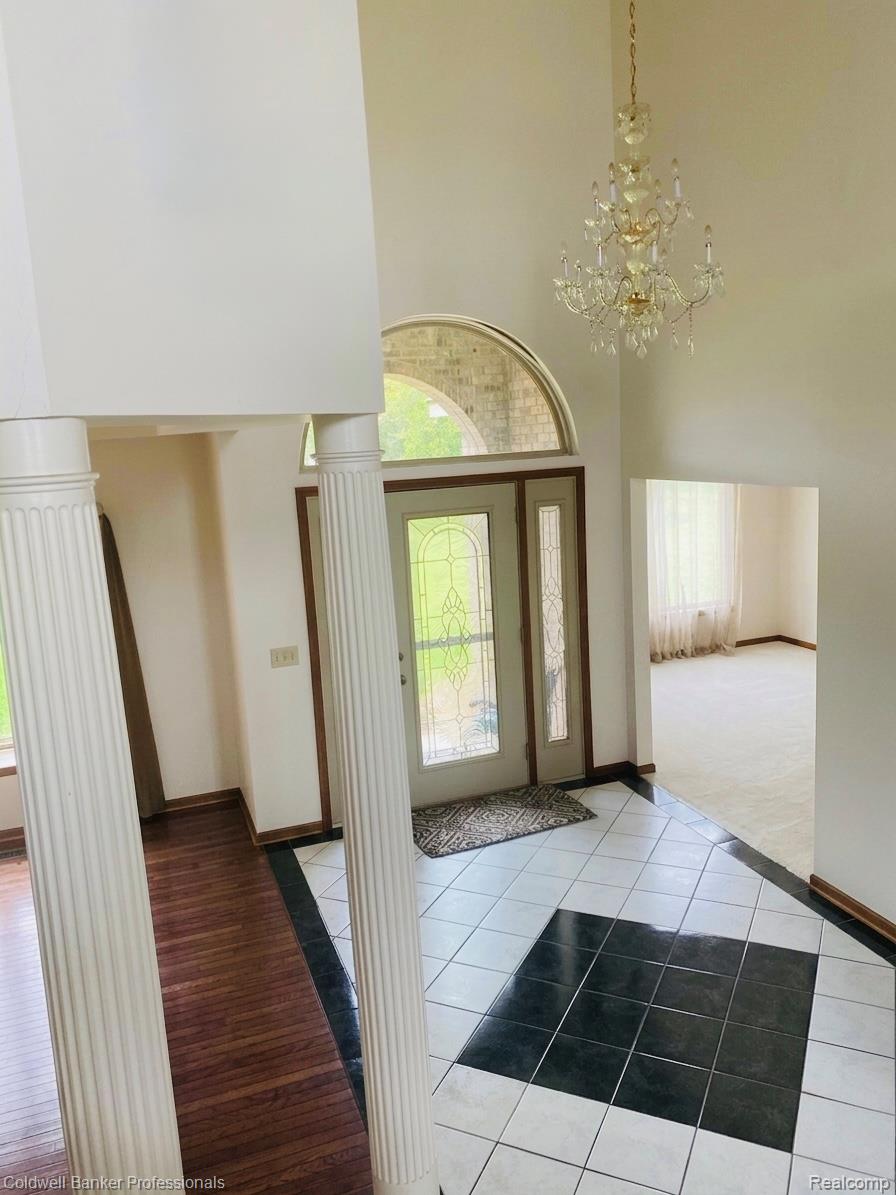 11171 Lapeer Road Davison, MI 48423 - Photo 38 of 42 Entryway featuring light tile patterned flooring, a chandelier, plenty of natural light, a high ceiling, and decorative columns
