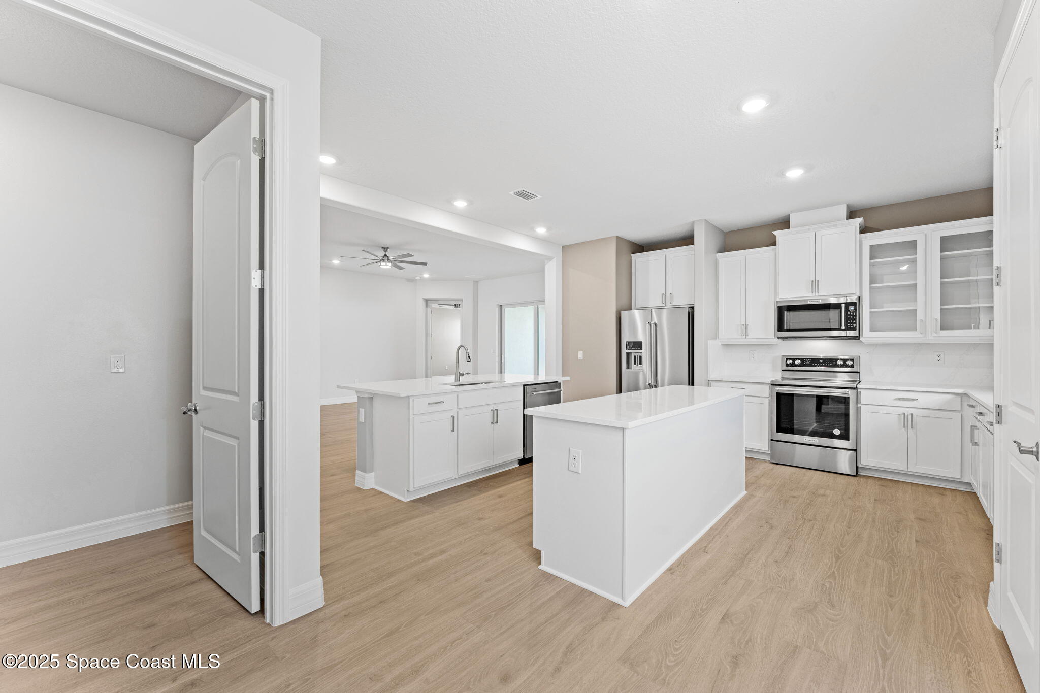 225 1st Street Cocoa, FL 32922 - Photo 38 of 64 a large white kitchen with stainless steel appliances granite countertop a refrigerator oven a sink and white cabinets with wooden floor