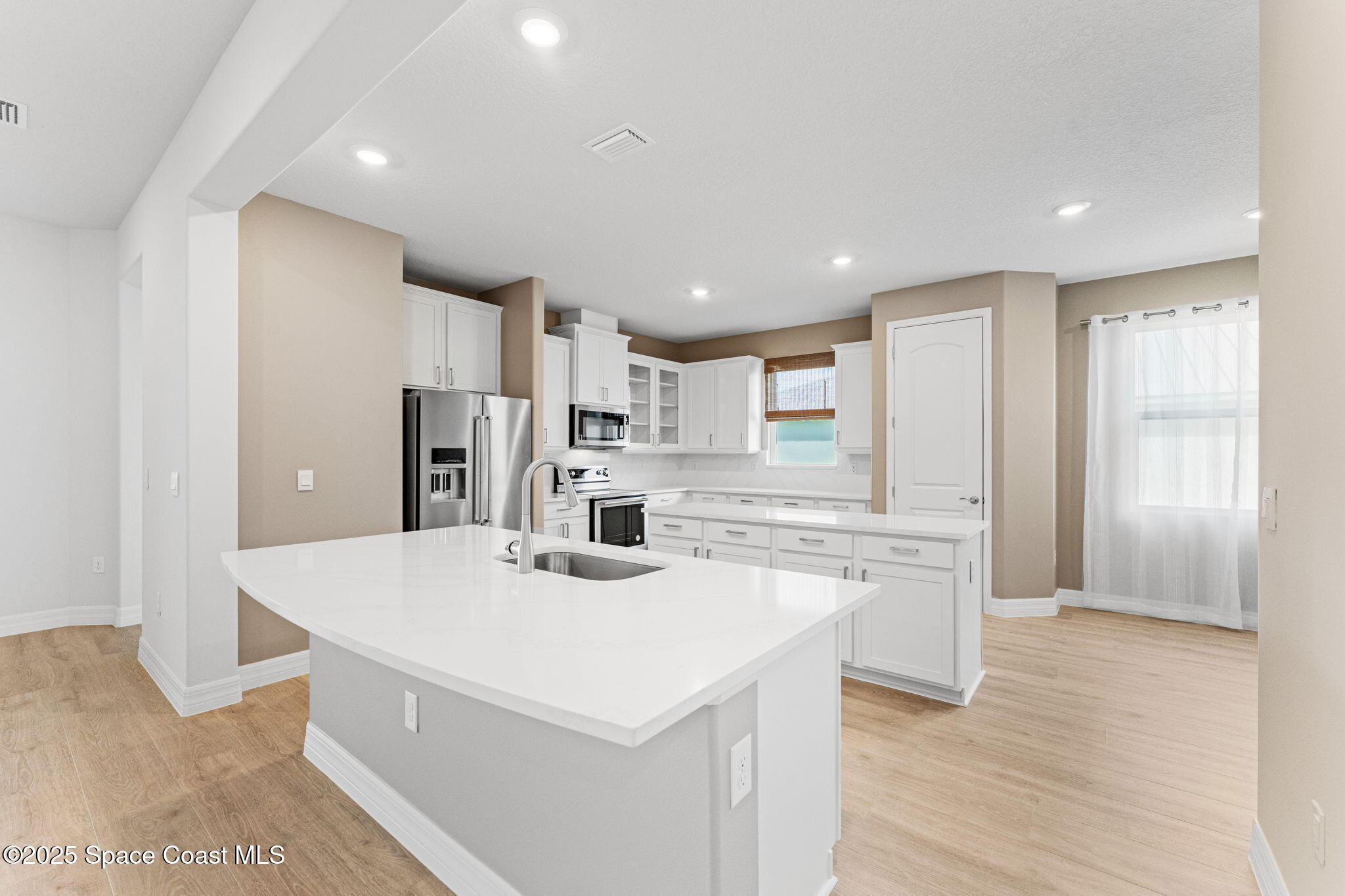 225 1st Street Cocoa, FL 32922 - Photo 4 of 64 a large kitchen with kitchen island a sink a stove a refrigerator and white cabinets