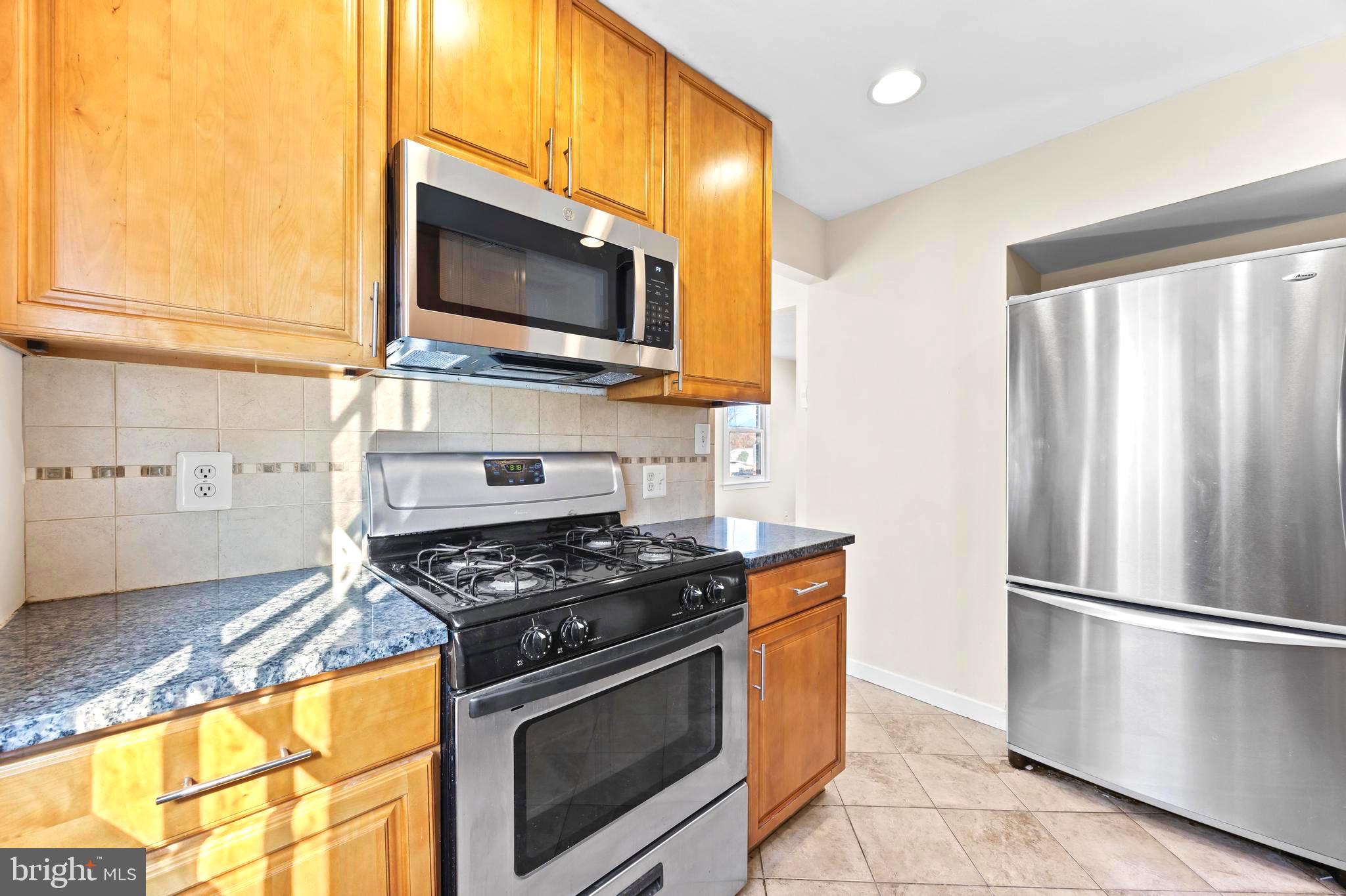 4605 Akron Street Temple Hills, MD 20748 - Photo 19 of 38 a kitchen with stainless steel appliances a stove a microwave a sink and cabinets