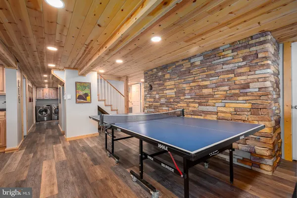 a living room with table tennis pool table and couches with wooden floor