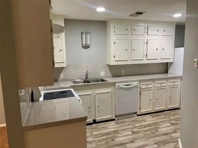 a kitchen with granite countertop a stove a sink and white cabinets