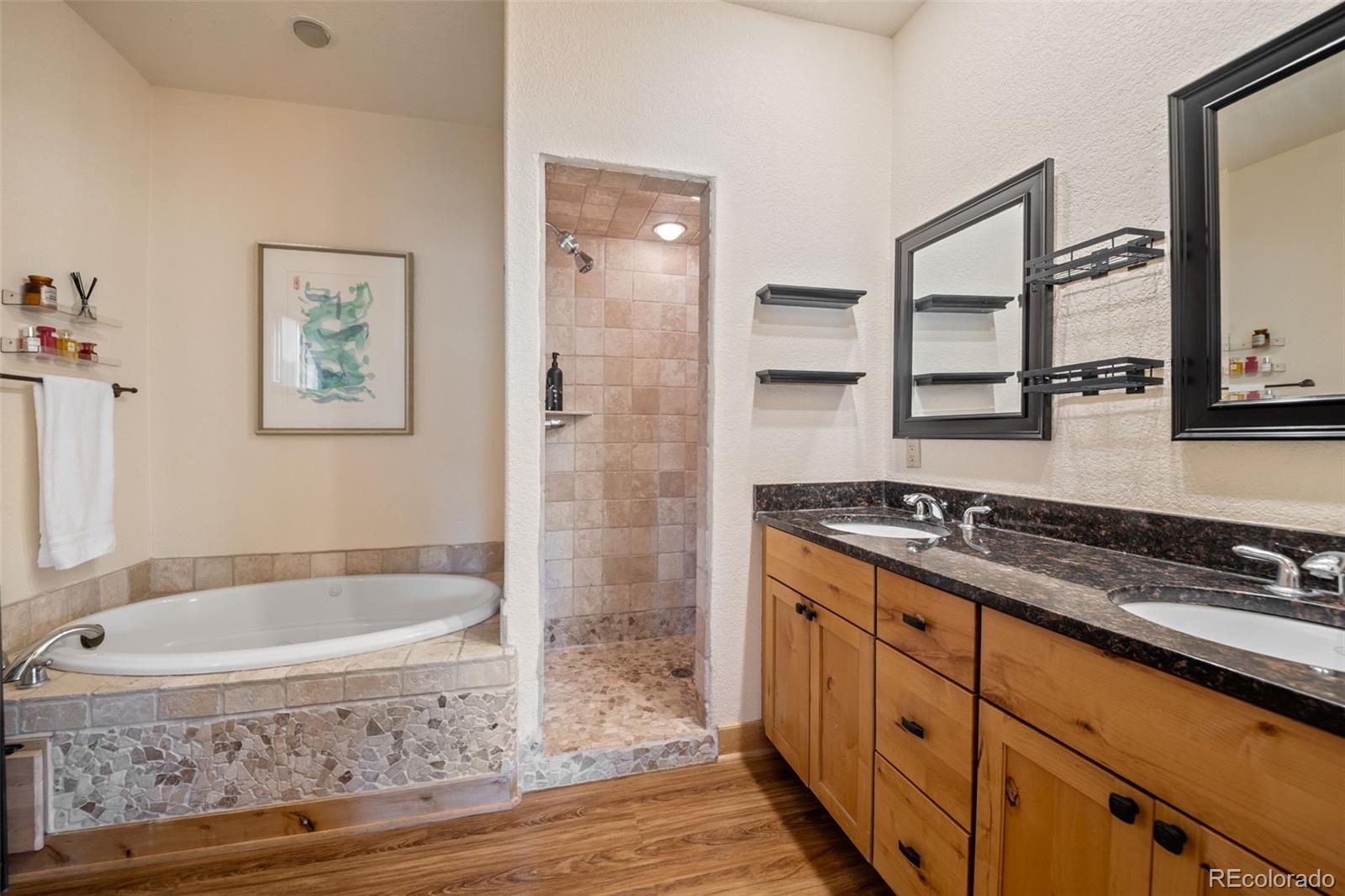 7102 Lynx Lair Road Evergreen, CO 80439 - Photo 18 of 42 a bathroom with a granite countertop sink a mirror a bathtub and shower
