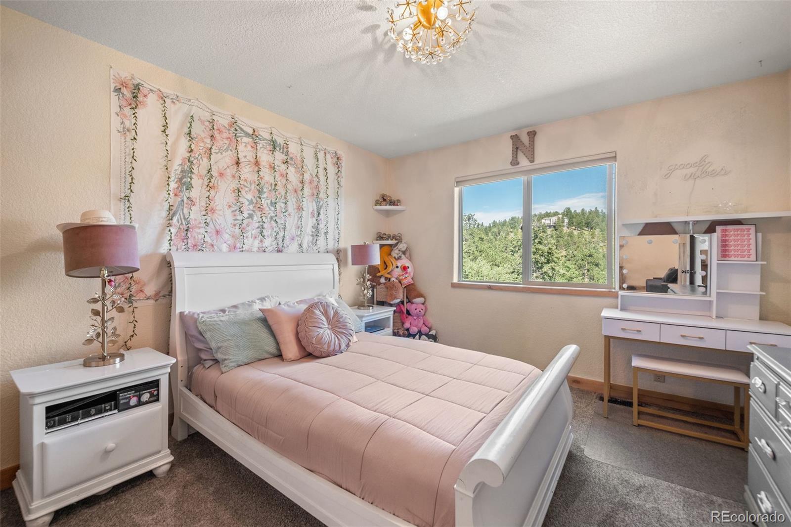 7102 Lynx Lair Road Evergreen, CO 80439 - Photo 23 of 42 a bedroom with a bed and a chandelier