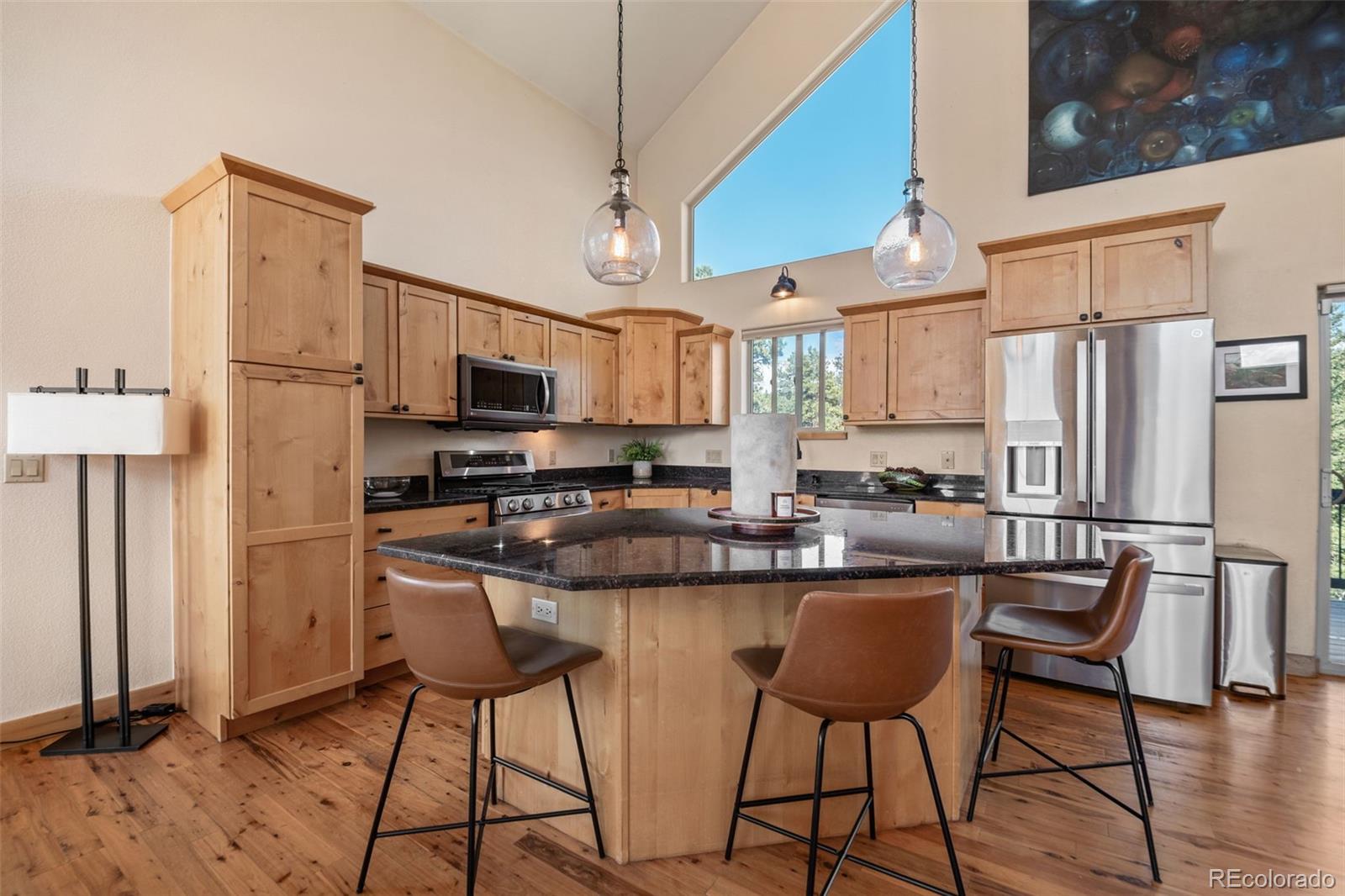 7102 Lynx Lair Road Evergreen, CO 80439 - Photo 9 of 42 a kitchen with stainless steel appliances granite countertop a stove a refrigerator a kitchen island a dining table and chairs