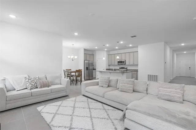 a living room with furniture white walls and white kitchen view