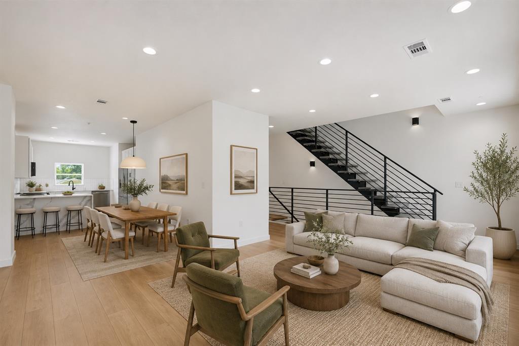 504 South O Connor Road Irving, TX 75060 - Photo 2 of 25 Open-concept living area featuring light wood-finish flooring, recessed lighting, and a contemporary staircase with black metal railings