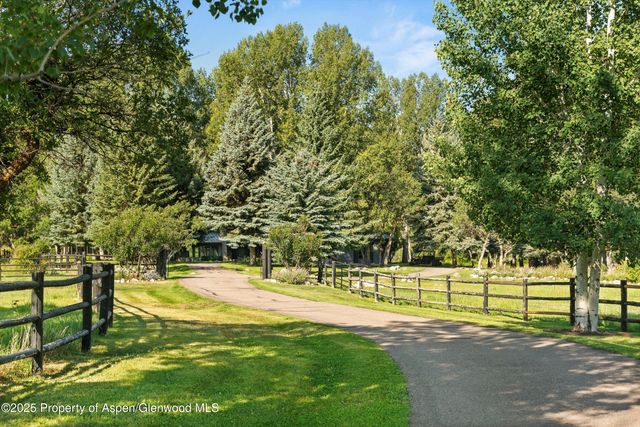 a view of a white house with a big yard and potted plants