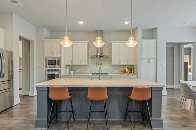 a kitchen with a dining table chairs cabinets and stainless steel appliances