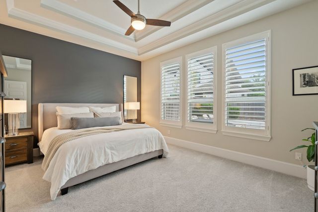 a bedroom with a large bed and a chandelier fan