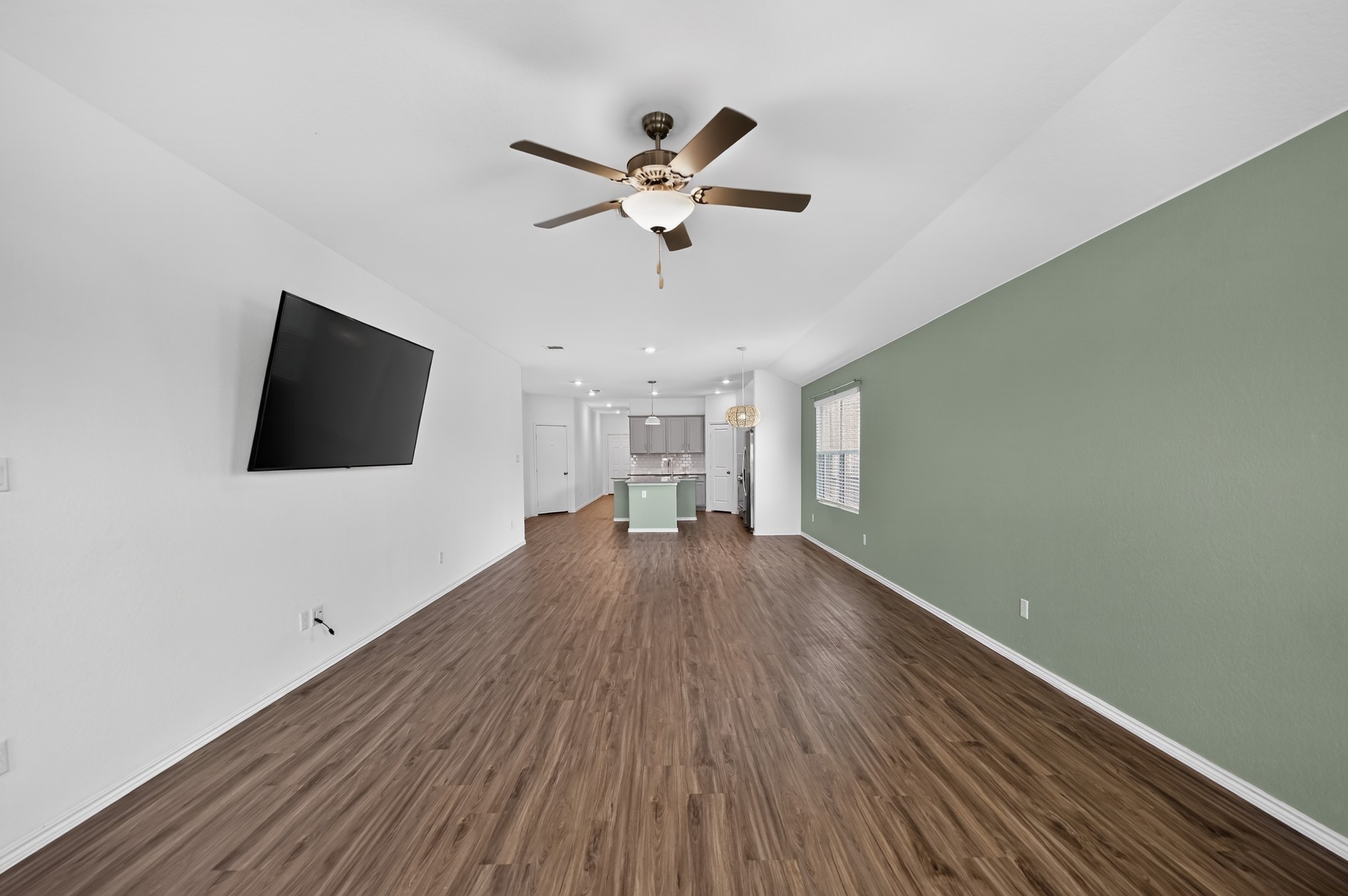 128 Konik Road Georgetown, TX 78626 - Photo 5 of 34 Natural light illuminates this open-concept space, revealing rich wood flooring and a contemporary kitchen beyond.