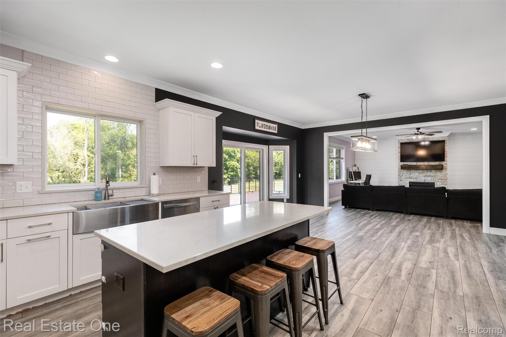 2983 28 Mile Road Washington, MI 48094 - Photo 12 of 54 Kitchen featuring a large center island with seating, stainless steel farmhouse sink, white shaker cabinetry, and light-toned subway tile backsplash