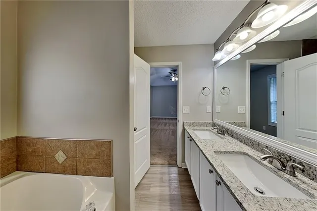 a bathroom with a granite countertop double vanity sink and mirror