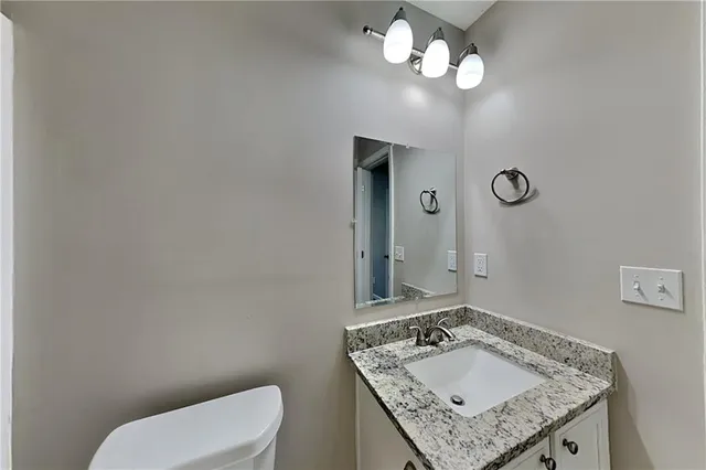 a bathroom with a granite countertop toilet sink and mirror