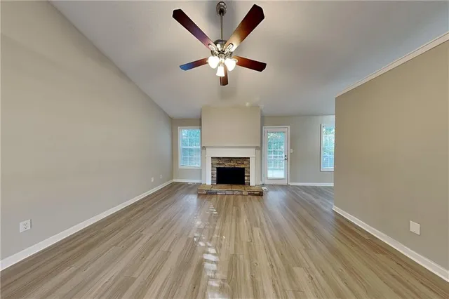 a view of an empty room with wooden floor and a fireplace