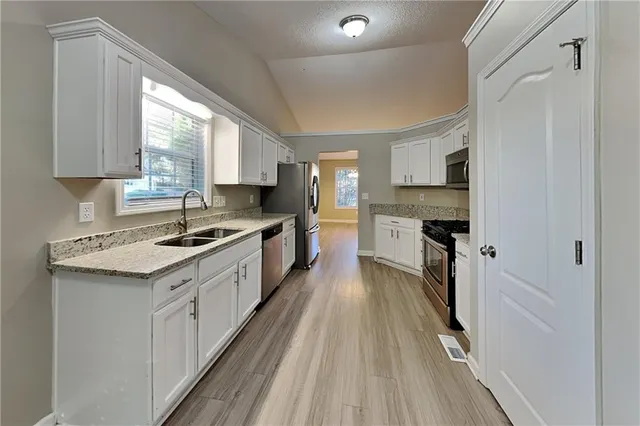 a large kitchen with granite countertop a stove top oven a sink a counter space and cabinets