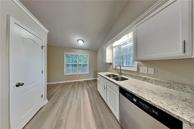 a kitchen with granite countertop stainless steel appliances a sink window and cabinets