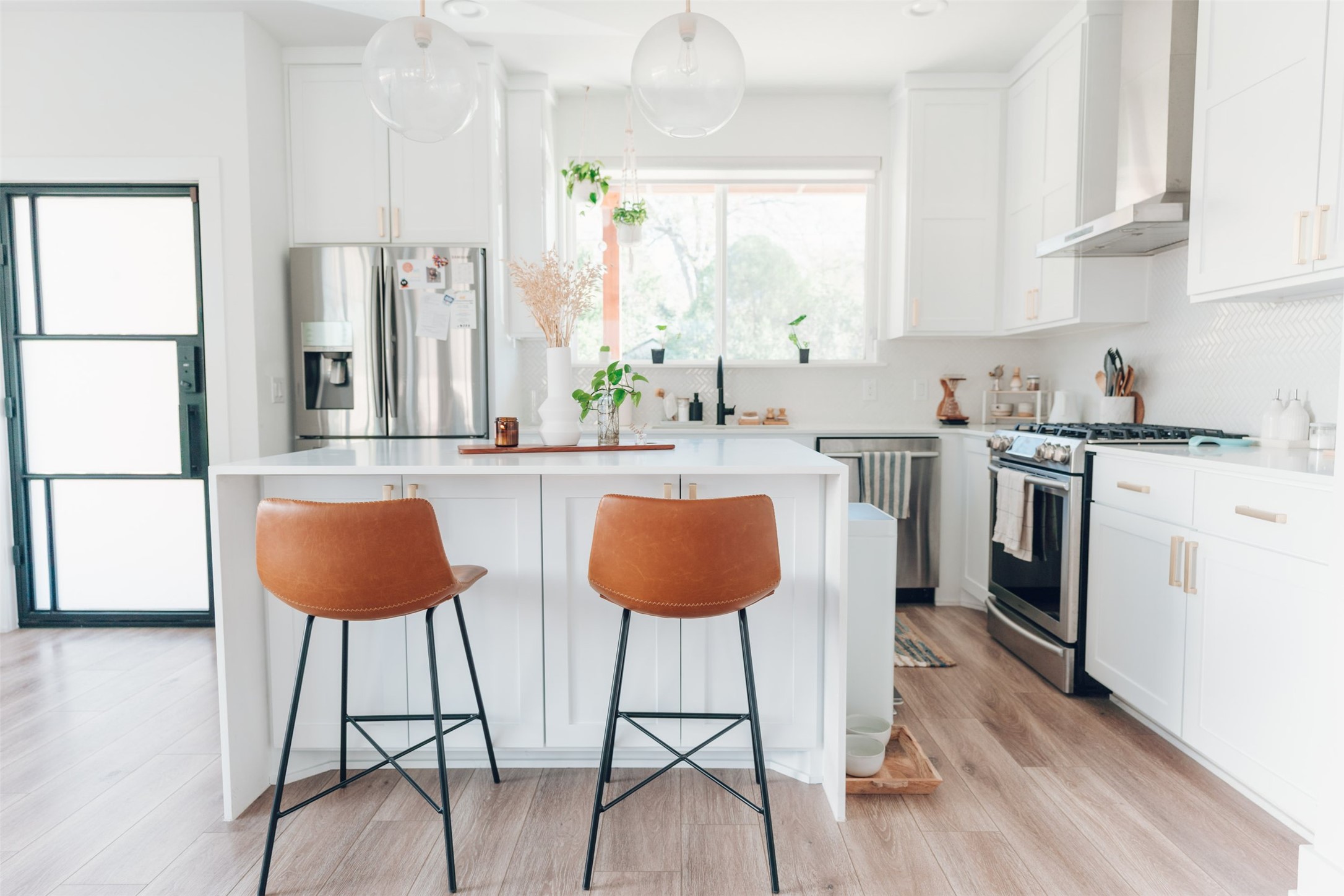 1106 Walton Lane, Unit B Austin, TX 78721 - Photo 4 of 28 Kitchen with stainless steel appliances, a center island, decorative light fixtures, white cabinetry, and light wood-type flooring