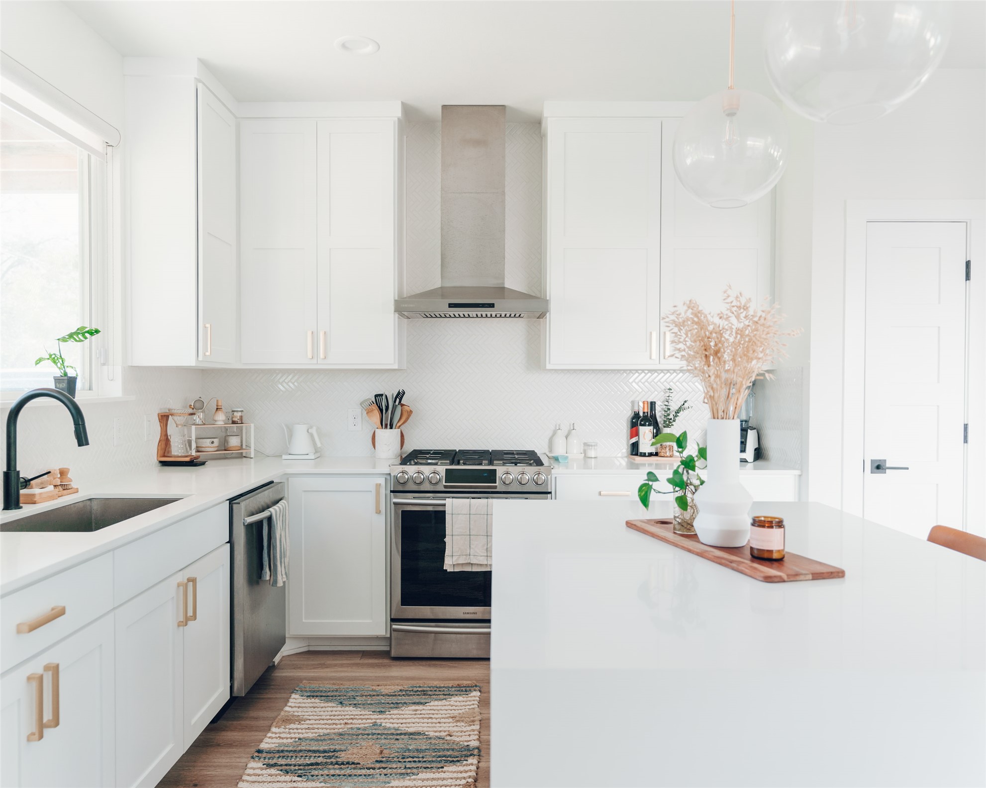 1106 Walton Lane, Unit B Austin, TX 78721 - Photo 5 of 28 Kitchen with white cabinetry, stainless steel appliances, decorative light fixtures, light wood-type flooring, and light stone counters