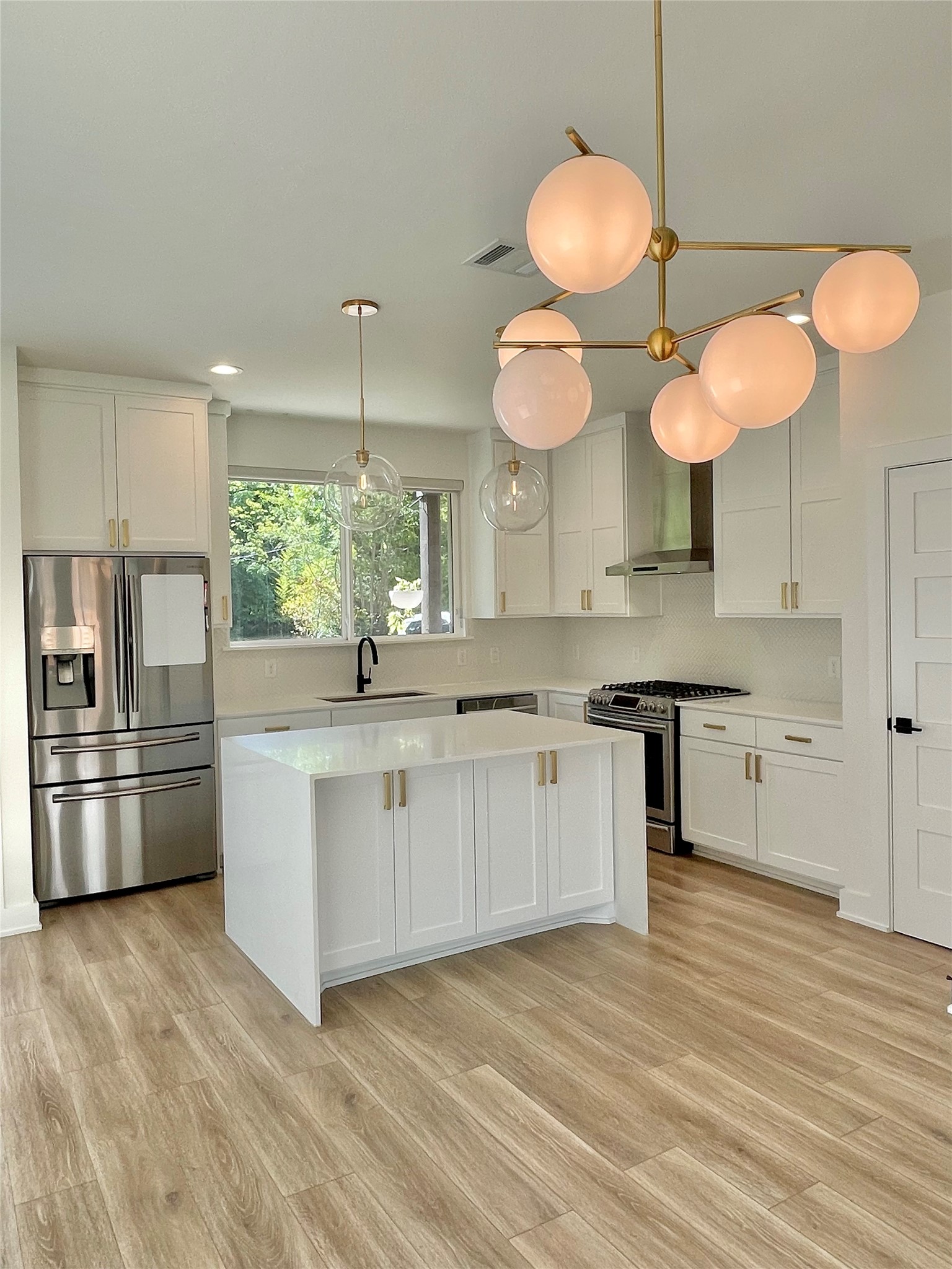 1106 Walton Lane, Unit B Austin, TX 78721 - Photo 6 of 28 Kitchen with white cabinets, stainless steel appliances, a center island, and tasteful backsplash