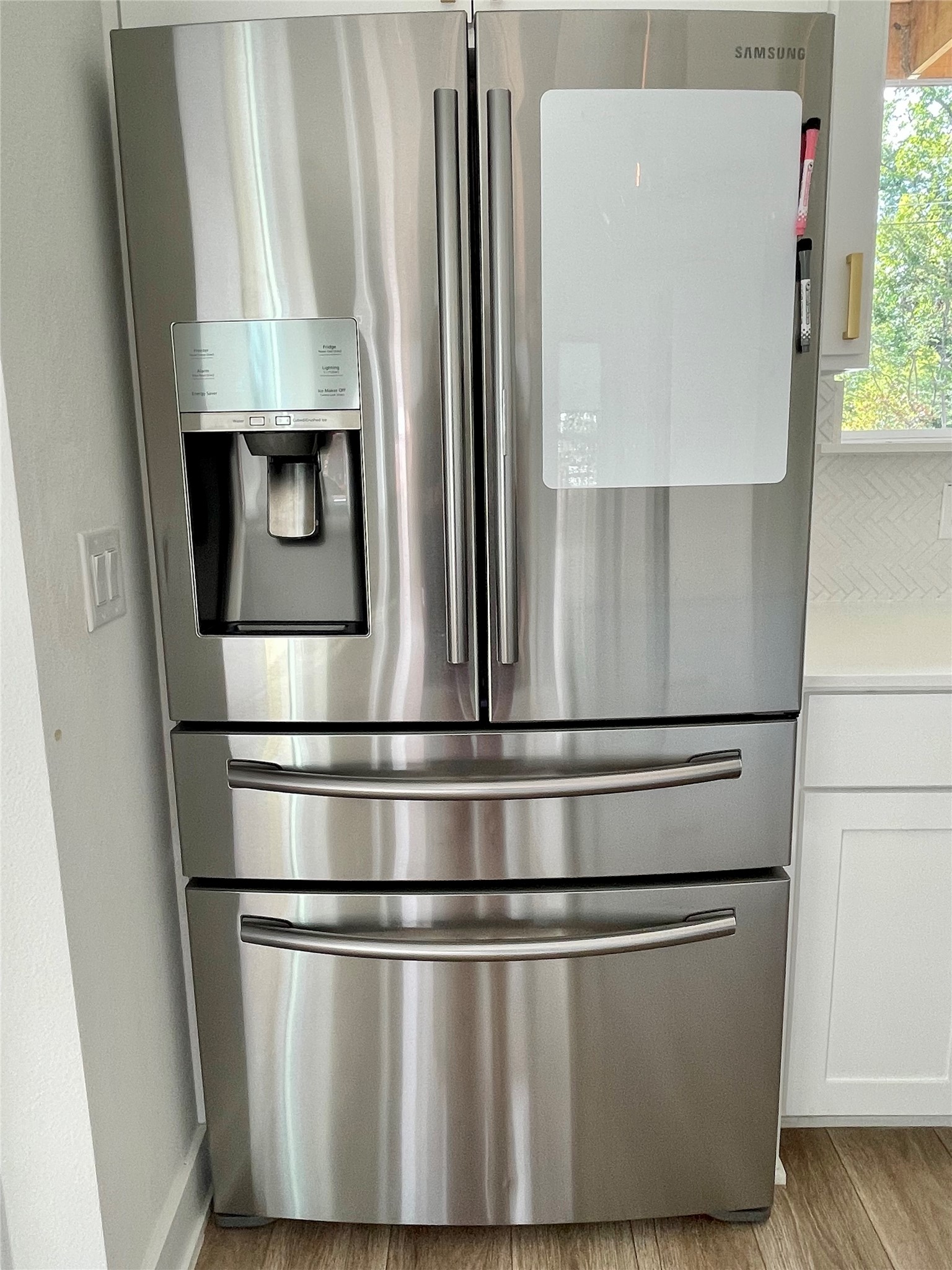 1106 Walton Lane, Unit B Austin, TX 78721 - Photo 7 of 28 Kitchen view of stainless steel refrigerator with ice dispenser, white cabinetry, and light wood-type flooring