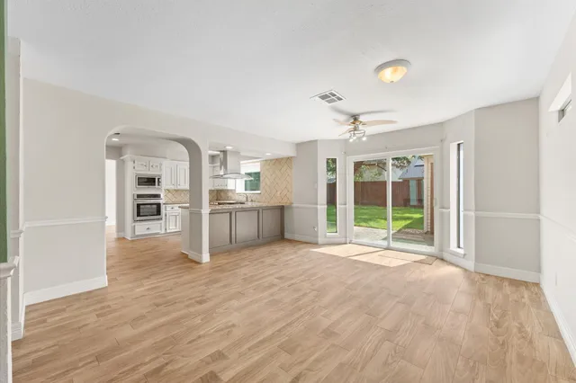 a view of an empty room with a window and kitchen view