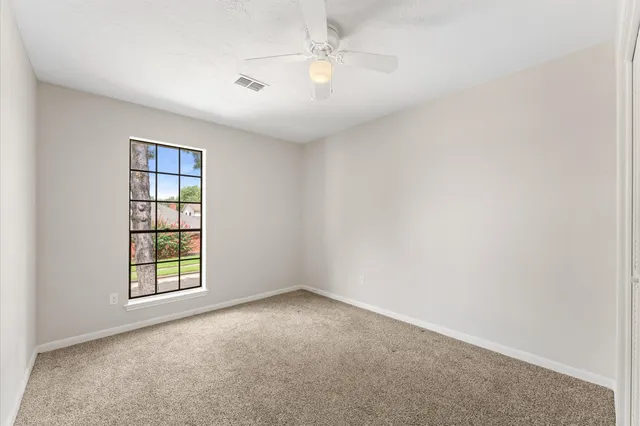 an empty room with windows and chandelier fan