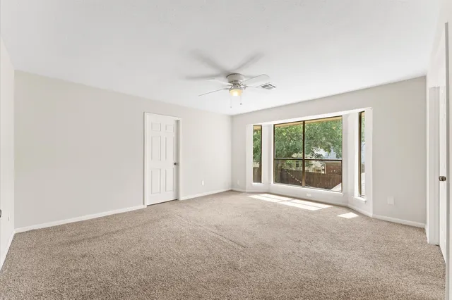 a view of a big room with windows and chandelier fan