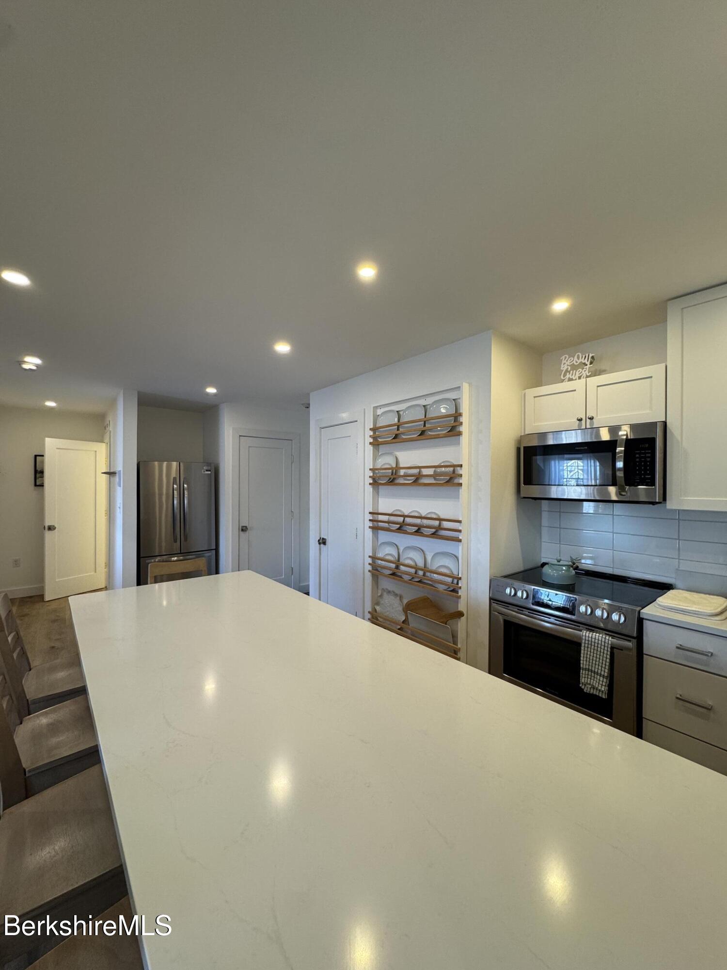 803 Crane Hancock, MA 01237 - Photo 10 of 24 a large white kitchen with kitchen island a stove a sink a refrigerator and a counter top space