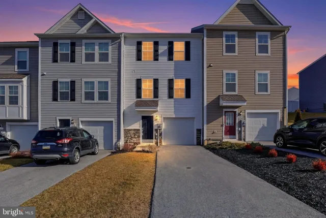 a front view of a house with cars parked