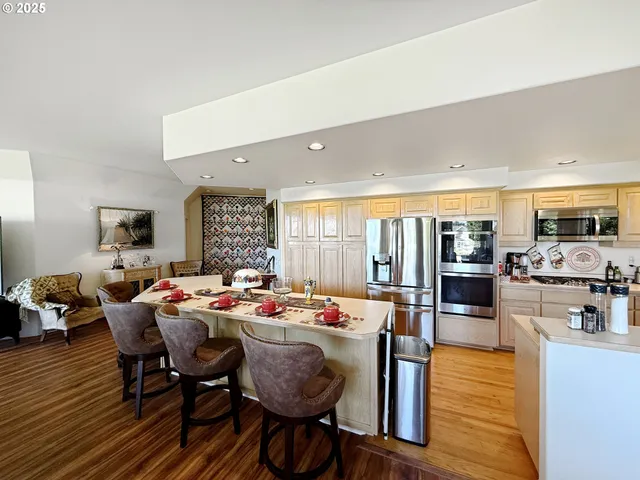 a dining room with wooden floor furniture and kitchen view
