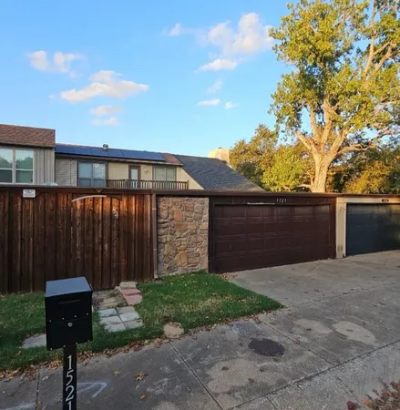 a backyard of a house with plants and wooden fence