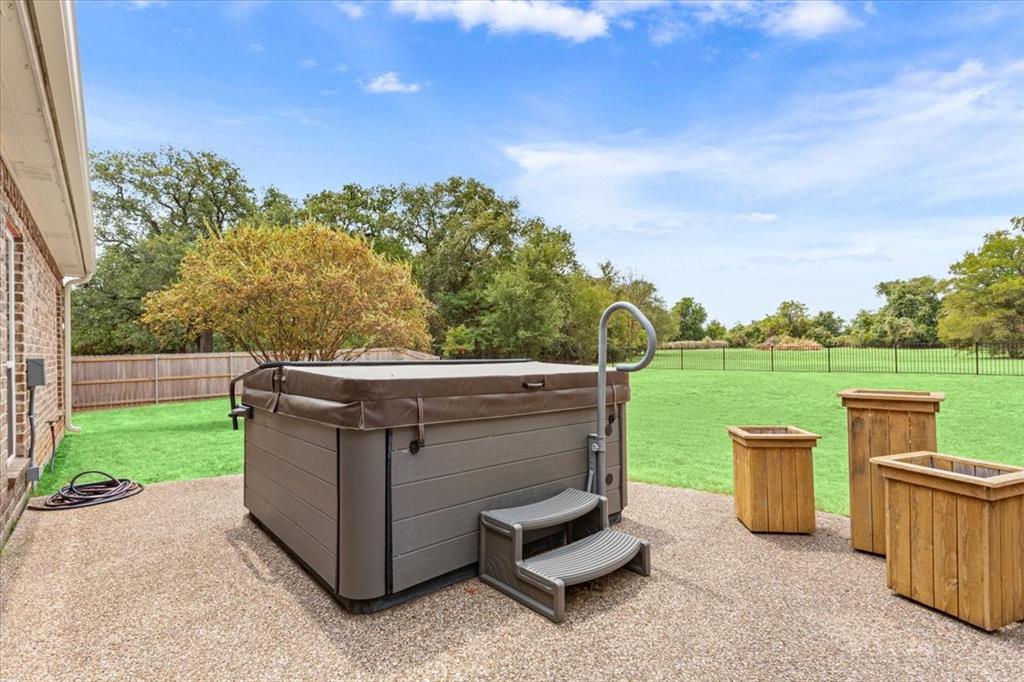 111 Spring Creek Street Waco, TX 76705 - Photo 37 of 40 Expansive outdoor patio featuring a hot tub with steps, a metal handrail, and a surrounding lawn