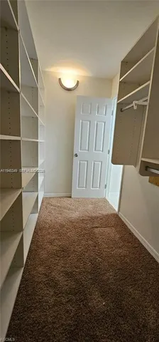 an empty room with closet and a chandelier fan