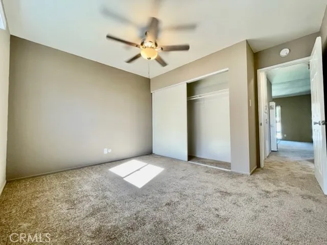 an empty room with a chandelier fan and closet