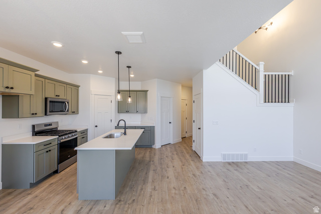 4752 Heartwood Road, Unit 433 Mapleton, UT 84664 - Photo 11 of 20 Kitchen featuring stainless steel appliances, light wood-style flooring, a center island with sink, light stone counters, and pendant lighting
